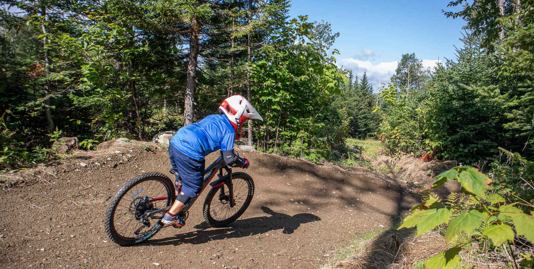 Child mountain biker blue shirt coming around a berm